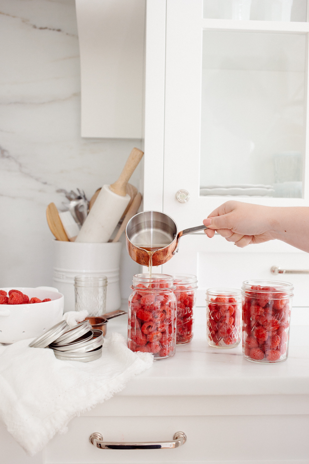 Pouring syrup into jars of raspberries