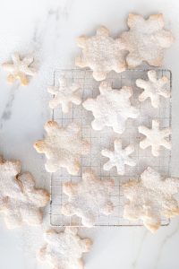 small and large snowflake cookies on marble countertop