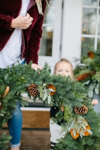toddler girl outside with large wreath
