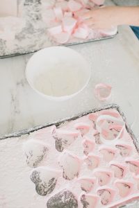 cutting out heart shaped marshmallows and rolling in powder sugar