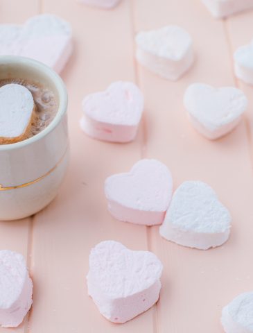 hot chocolate in ceramic mug with heat shaped marshmallow and marshmallows around the mug