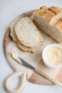 country style bread on wooden board with butter in dish