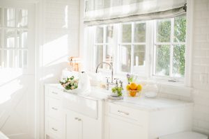 airy white kitchen with florals and fruit on the counter