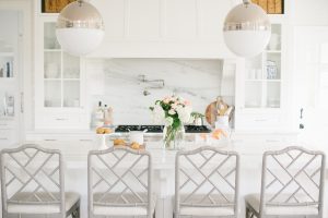 white kitchen with large marble island and pendant lighting