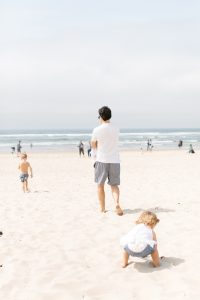 dad walking on the beach with kids