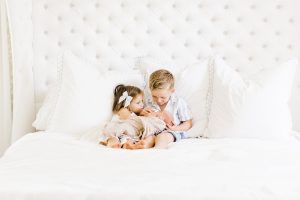 brother and sister cuddling baby brother in bed