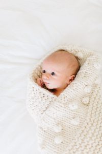 newborn in knitted cream blanket