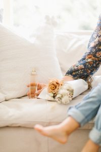 pretty perfume bottle on couch by flowers