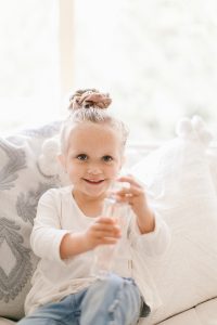 little girl with scrunchies in her hair holding perfume