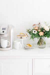 coffee maker with muffins and florals on counter
