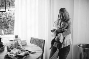 mom comforting baby boy, clothes on table