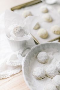 almond snowball cookies being tossed in powder sugar