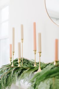 White and Pink candles on a green garland as fireplace decor