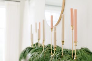 White and Pink candles on a green garland as fireplace decor