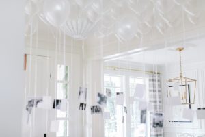 inflated white balloons with black and white photos attached in a white room