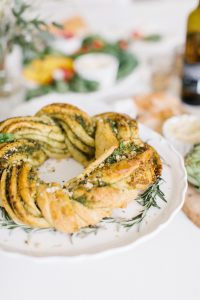 braided pesto wreath bread on white cake platter