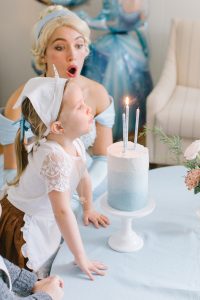 birthday girl blowing out cinderella cake candles