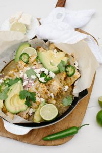 green chili chicken enchiladas in skillet with queso