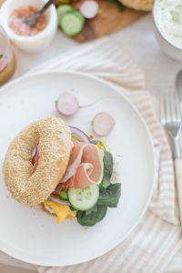 bagel sandwich on table with prosciutto and cucumbers