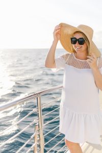 woman on boat in white dress, straw hat and sunglasses