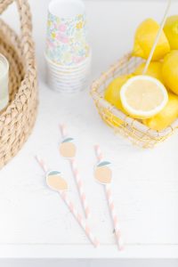 paper lemon prints on straws next to a basket of lemons