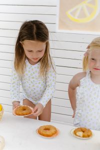two young girls with lemon outfits eating donuts