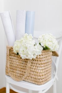 Basket on White Chair Displaying the #MHxUrbanWalls Wallpaper Rolls with Fresh Hydrangeas