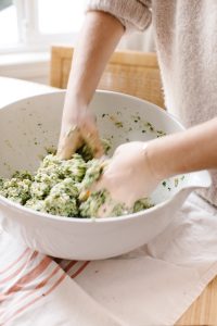 Hand Mixing Loaded Green Chicken Meatballs in Bowl