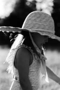 little girl wearing straw hat and swimsuit walking through grass