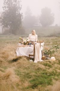 Monika Hibbs in a field next to a table with flowers